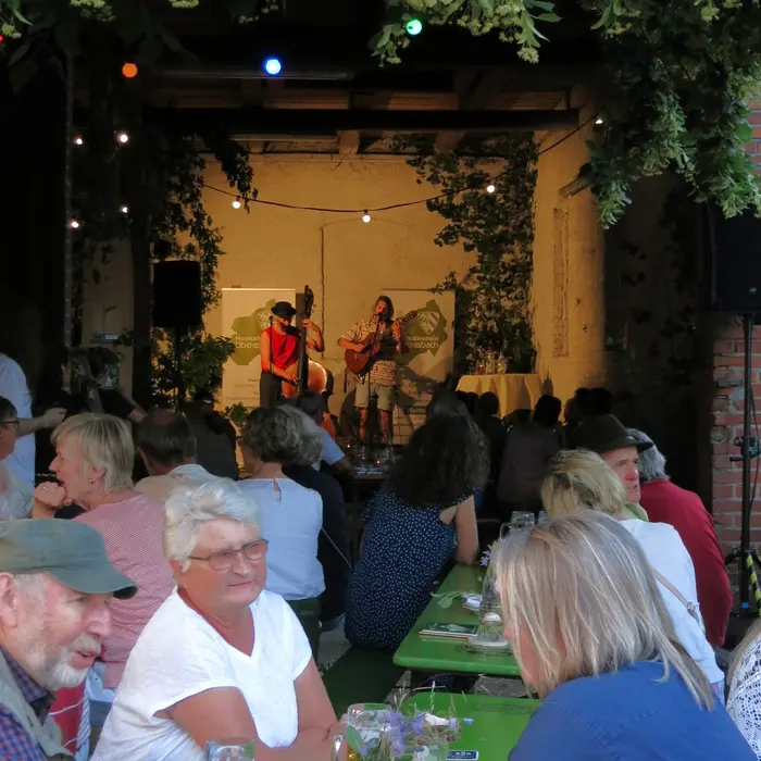 Viele Menschen an Biertischen in einer geschmückten Scheune 