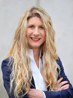 junge Frau mit blonden langen Locken, weißer Bluse und blauer Anzugsjacke 