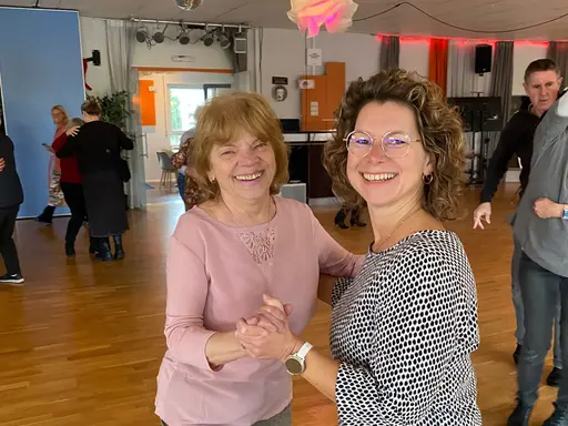 Zwei Frauen tanzen Standardtanz in einer Tanzschule. Im Hintergrund andere Gäste.