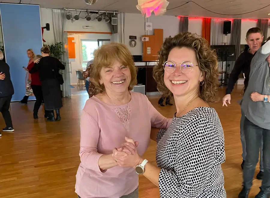 Zwei Frauen tanzen Standardtanz in einer Tanzschule. Im Hintergrund andere Gäste.