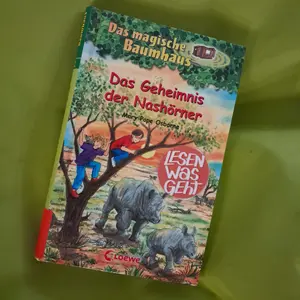 Titelbild des Buches "Das Geheimnis der Nashörner" in der Reihe "Das magische Baumhaus" auf einer grünen Decke. 