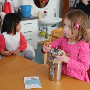 Ein Mädchen mahlt Kaffeebohnen in einer Kaffeemühle