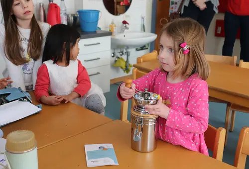 Ein Mädchen mahlt Kaffeebohnen in einer Kaffeemühle