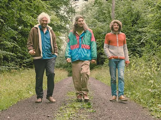 Plakat: Drei junge Männer auf einem Waldweg, Schrift: Etz is etz Kapelle Bomhard