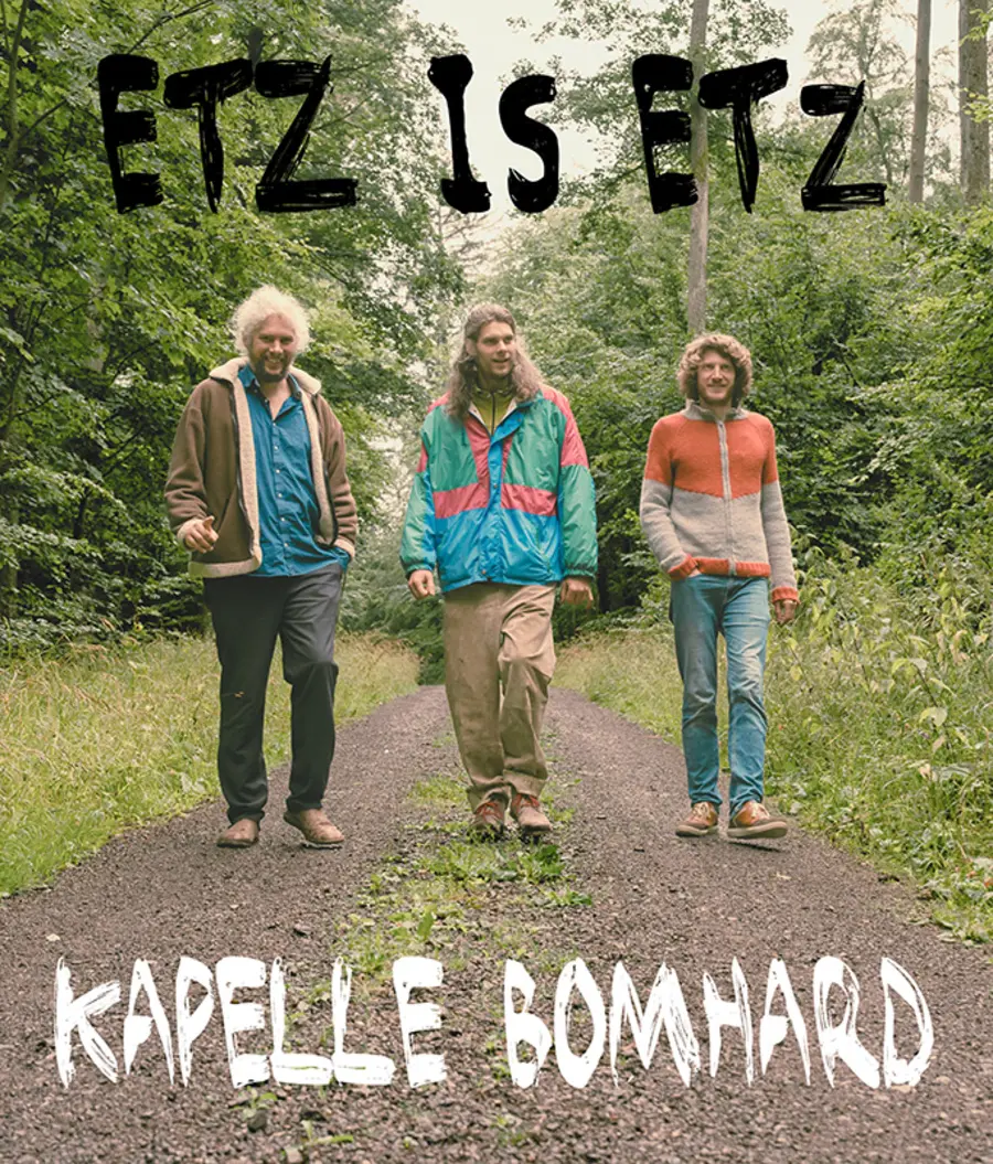 Plakat: Drei junge Männer auf einem Waldweg, Schrift: Etz is etz Kapelle Bomhard