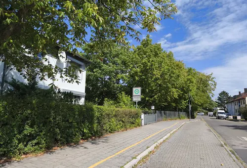 Blick eine Straße entlang; in der Mitte des Bildes das Schild einer Bushaltestelle