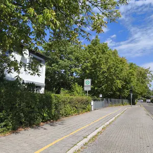 Blick eine Straße entlang; in der Mitte des Bildes das Schild einer Bushaltestelle