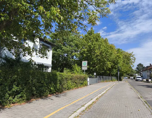 Blick eine Straße entlang; in der Mitte des Bildes das Schild einer Bushaltestelle 