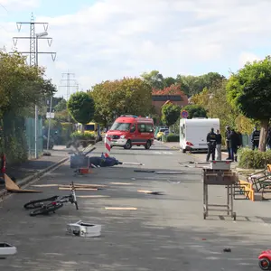 umgekippte Bänke und Tische des Straßenfest, im Hintergrund ein FW-Wagen.