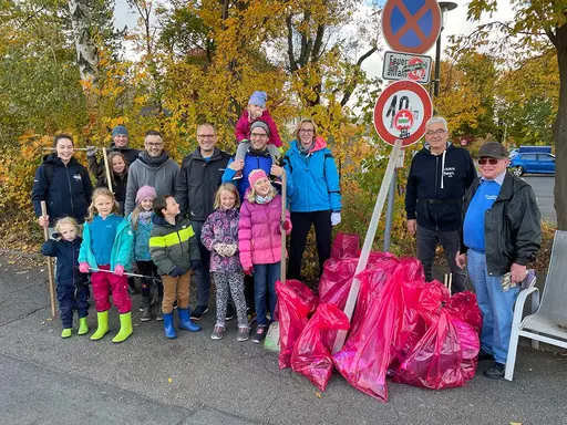 Gruppe von Erwachsenen, Jugendlichen und Kindern mit ihren gesammelten Müllsäcken.
