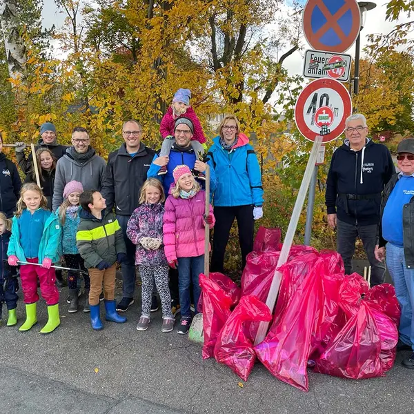 Gruppe von Erwachsenen, Jugendlichen und Kindern mit ihren gesammelten Müllsäcken.