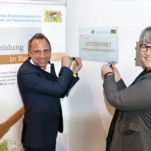 Ein Mann und eine Frau schrauben ein Schild an die Wand.