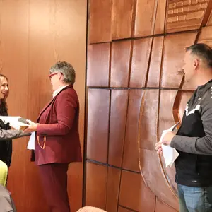 ein Mann, eine Frau und eine junge Frau mit Urkunde 