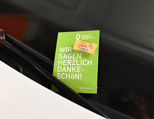 Karte mit Süßigkeit klemmt unter einem Scheibenwischer