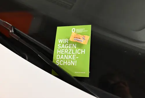 Karte mit Süßigkeit klemmt unter einem Scheibenwischer