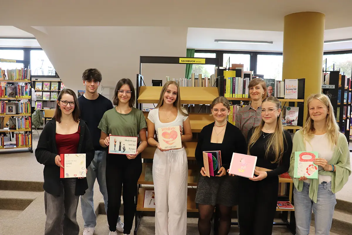 Ein Schüler und sechs Schülerinnen präsentieren ihre Bücher. Im Hintergrund steht die Lehrerin.