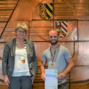 Ein Mann hat eine Urkunde von einer Frau erhalten.