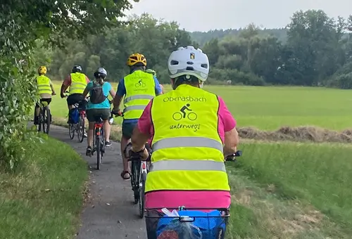 Eine Gruppe von Rafahrern mit gelben Warnwesten mit der Aufschrift "Oberasbach unterwegs"