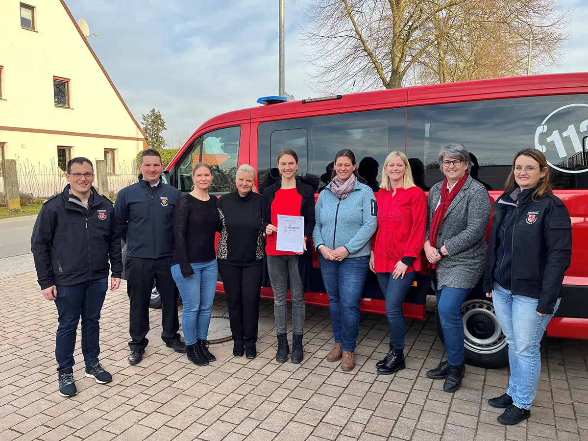 Die vier Gruppenleiterinnen mit den Gratulierenden vor dem Feuerwehrfahrzeug