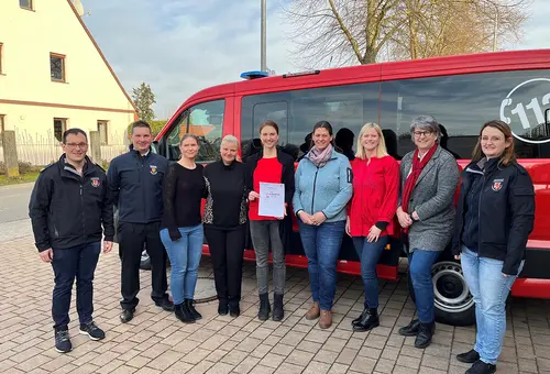 Die vier Gruppenleiterinnen mit den Gratulierenden vor dem Feuerwehrfahrzeug