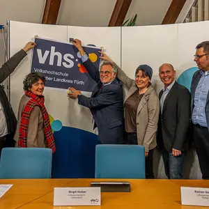 Drei Frauen und drei Männer befestigen ein Logo-Schild an einem Display.