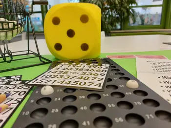 Bingospiel, Würfel und Quizfragen auf einem Tisch.
