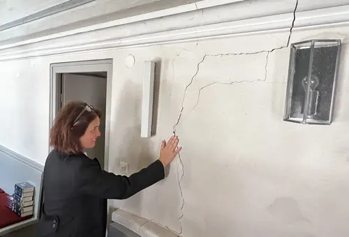 Pfarrerin legt Hand auf Wand