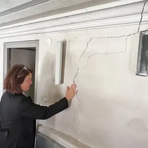 Pfarrerin legt Hand auf Wand