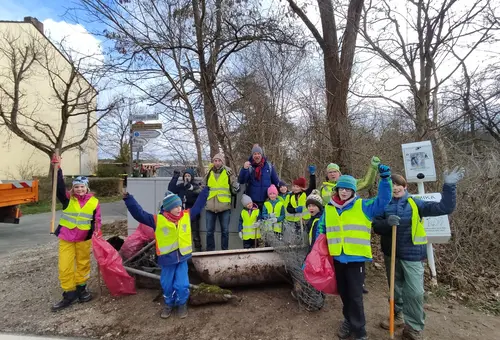 Gruppe von Erwachsenen und Kindern mit Badewanne, Waschbecken und Maschendraht