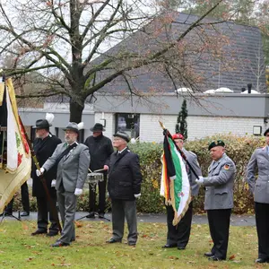 Eine Gruppe von Schützen in Anzügen und mit Fahne links im Bild, rechts Vertreter der Bundeswehr mit Fahne.