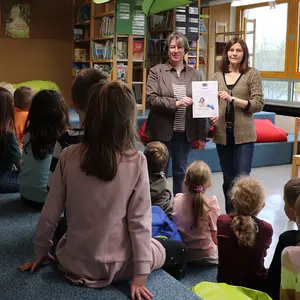Rektorin Gabriele Eitel und Claudia Walther präsentieren den lesebegeisterten Kindern die Urkunde zum Gütesiegel.