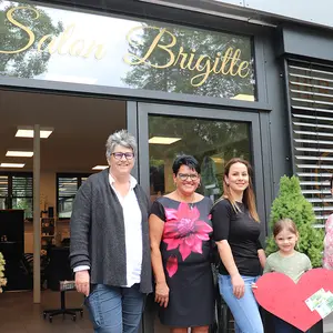 Vier Frauen und ein Kind vor dem Eingang des Salon Brigitte.