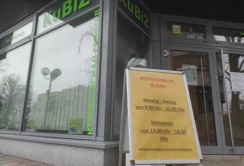 Schild vor einer Glasfront mit den Öffnungszeiten des Briefwahlzentrums.
