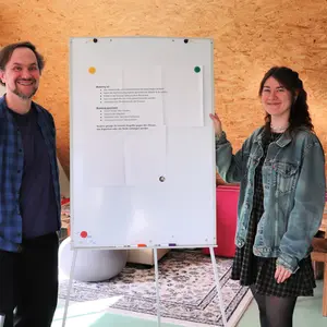 zwei Sozialpädagog:innen neben einem Flipchart 