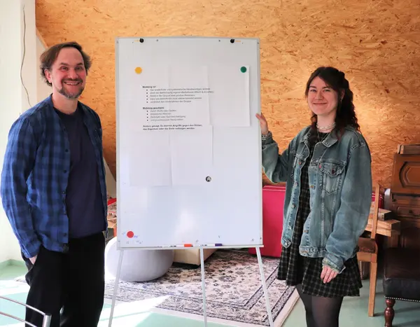 zwei Sozialpädagog:innen neben einem Flipchart 