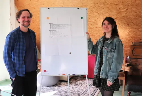 zwei Sozialpädagog:innen neben einem Flipchart 