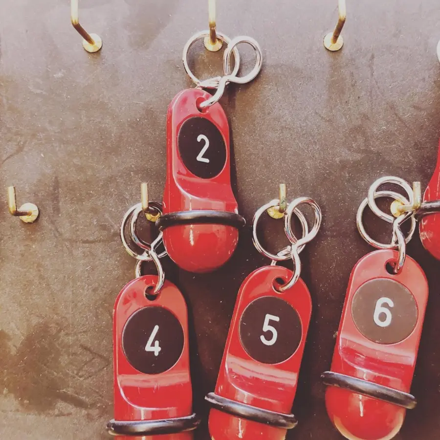 Schlüsselbrett mit Haken, an denen Schlüssel für Hotelzimmer hängen. Die Anhänger tragen die Zahlen 2, 4, 5 und 6.