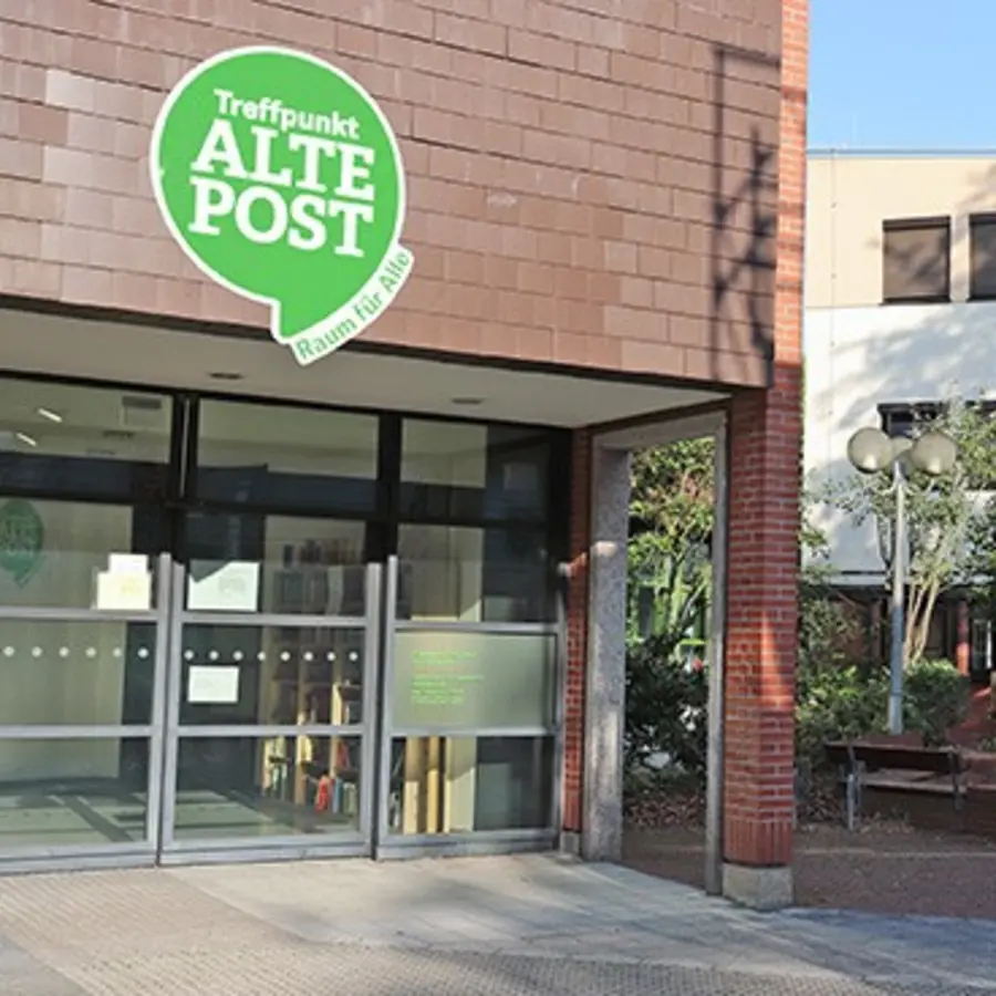 Eingangsbereich des Treffpunkts Alte Post mit dem grünen Logo über der Tür