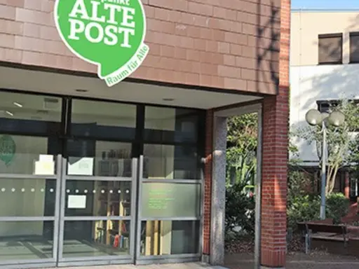 Eingangsbereich des Treffpunkts Alte Post mit dem grünen Logo über der Tür