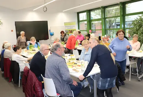 Tafel in U-Form mit Seniorinnen und Senioren beim Frühstück