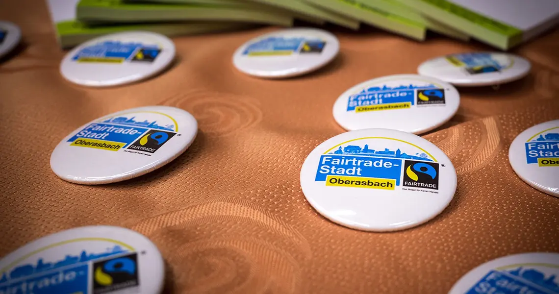 Ansteckbuttons mit Fair Trade Logoliegenauf einem Tisch (Großaufnahme)
