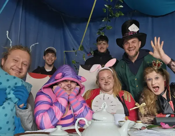 verkleidete Menschen in einem Zelt an einem Tisch mit Teegeschirr