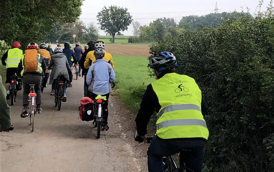 Eine Gruppe von Radfahren auf einem Waldweg. Der rechte Fahrer trägt eine Warnweste mit dem Aufdruck "Oberasbach unterwegs".
