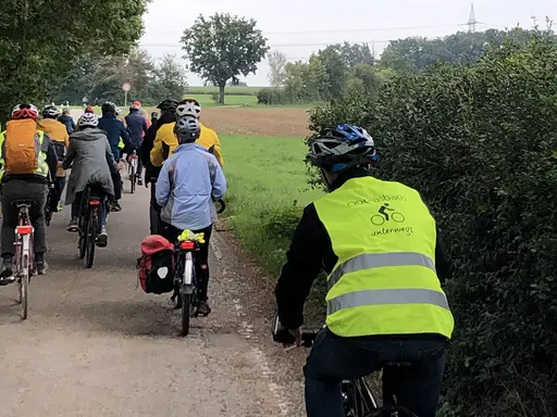Eine Gruppe von Radfahren auf einem Waldweg. Der rechte Fahrer trägt eine Warnweste mit dem Aufdruck "Oberasbach unterwegs".