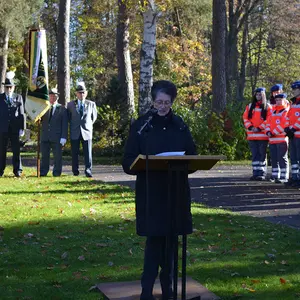 Eine Frau liest am Rednerpult auf der Rasenfläche am Mahnmal