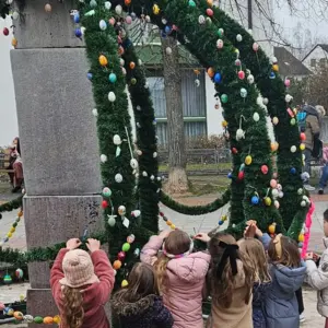Kinder hängen Eier an einem Osterbrunnen auf 
