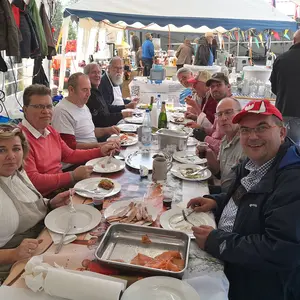 Rund zehn Personen sitzen an einer Tafel und essen zu Mittag.