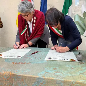 Zwei Frauen unterschreiben ein Dokument.