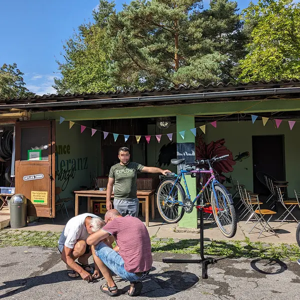 Mehrere Personen stehen um ein aufgebocktes Fahrrad im Innenhof des Jugendhauses.