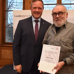 Zwei Männer, einer hält eine Urkunde.